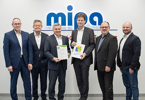 Districtsbestuurder van het district Landshut Peter Dreier (3e van links) overhandigt Mipa CEO Markus Fritzsche (4e van links) het certificaat voor de verlenging van het Beierse milieu- en klimaatpact.